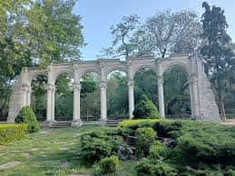 Fachada del pórtico de columnas y arcos rodeado de jardines y vegetación