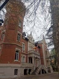 Ángulo inferior de la torre y entrada del Palacio de la Isla, con banderas y árboles en primer plano