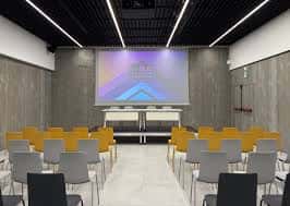 Sala de conferencias con proyector y sillas dispuestas para eventos