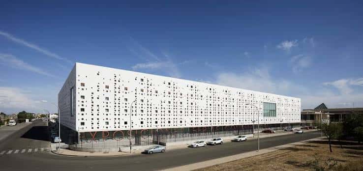 Vista exterior del Centro de Exposiciones de Córdoba con su fachada blanca perforada bajo un cielo azul