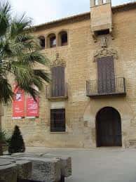 Vista lateral del museo con balcones de hierro forjado y carteles rojos en la entrada
