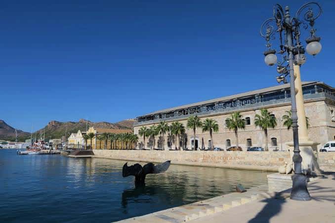 Fachada del Puerto de Culturas con escultura de ballena y palmeras