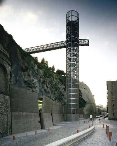 Fachada del ascensor panorámico integrado en la roca con acceso peatonal y señalización