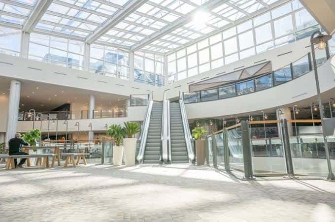 Área de descanso con escaleras mecánicas y techos de cristal