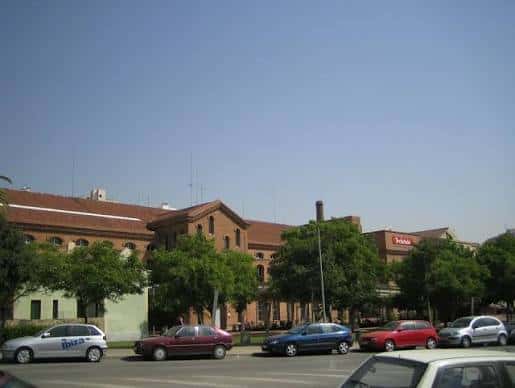 Vista general de la plaza con edificios de ladrillo y vehículos estacionados