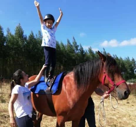 Niño celebrando sobre un caballo con apoyo de un adulto
