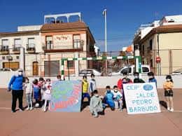Alumnos y personal del CEIP Pedro Barbudo en el patio con pancartas festivas