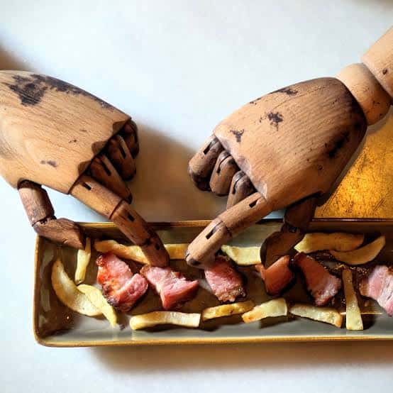 Plato de tapas servido en bandeja con manos de maniquí de madera