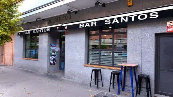 Fachada exterior del Bar Santos en Vitoria con mesas altas y sillas