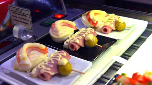 Platos de pinchos montados con jamón, queso y aceituna en el mostrador
