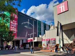 Fachada exterior de LaFACT con cartel de danza y personas en la plaza