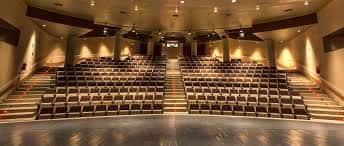 Sala de actos con gradas y iluminación cálida para eventos culturales