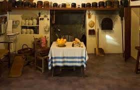 Interior del museo con exhibición de utensilios domésticos tradicionales y mesa con frutas