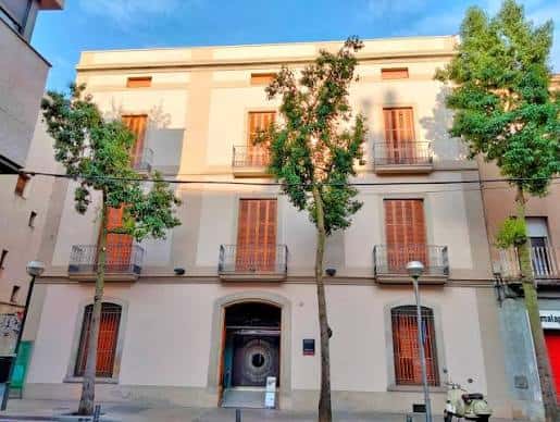Fachada principal del Museu d'Art de Sabadell con árboles y cielo azul
