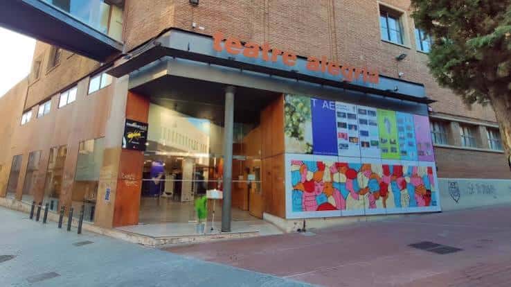 Entrada principal del teatro durante el día con cartelera de eventos