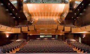 Interior del auditorio con butacas y escenario iluminado
