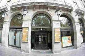 Entrada principal del edificio con arcos de piedra y carteles informativos