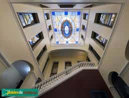 Interior del atrio con escalera de caracol y vitral decorativo en el techo
