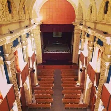 Vista aérea del interior del teatro con escenario y butacas naranjas