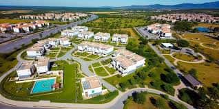 Vista aérea de una urbanización moderna con viviendas unifamiliares, piscina y amplias zonas ajardinadas