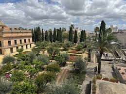 Vista panorámica de los jardines y edificios del Alcázar bajo cielo nublado