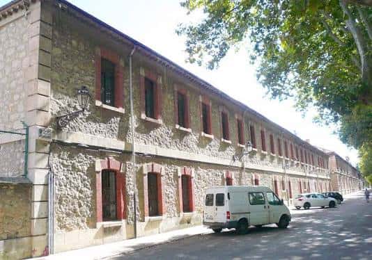 Vista exterior del Antiguo Hospital Militar en Burgos, actual Universidad de Burgos, con fachada de piedra y ventanas con marcos rojos