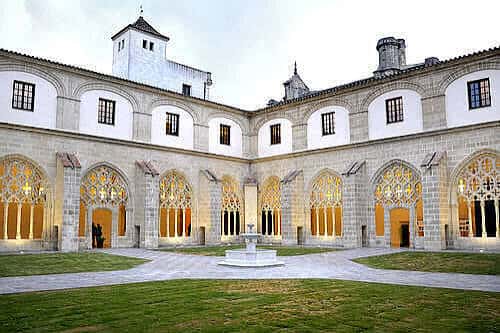 Claustro de Santo Domingo iluminado al atardecer con fuente central y arcos góticos