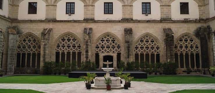 Vista frontal del claustro con arcos decorados y jardín central, ideal para eventos