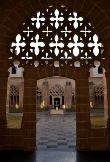 Detalle arquitectónico de los arcos calados del claustro con luz natural filtrándose