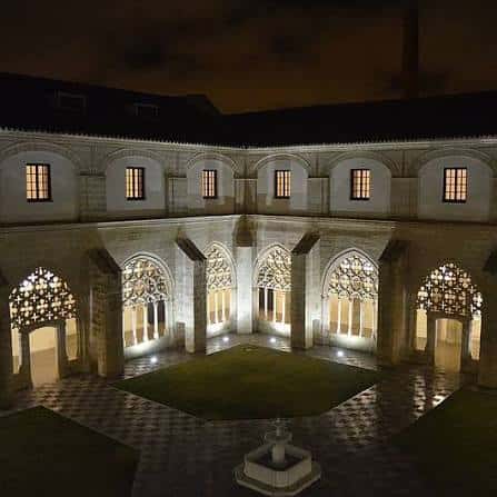 Claustro nocturno con iluminación cálida que resalta la arquitectura histórica