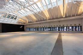 Interior amplio y vacío del espacio cultural con techo de cristal y estructura metálica blanca