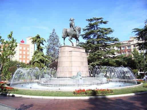Estatua ecuestre con fuente decorativa al frente en un día soleado
