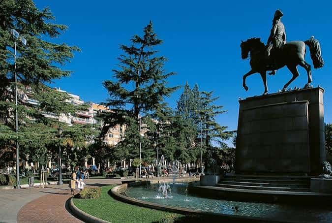 Plaza con estatua de jinete y fuente bajo cielo azul despejado