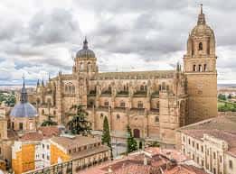 Vista panorámica de la Catedral Nueva de Salamanca con sus torres y cúpulas bajo cielo nublado