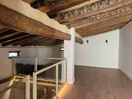Interior del espacio con vigas de madera y suelo de madera, ideal para eventos culturales
