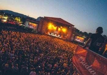 Escenario principal del festival al atardecer con multitud de asistentes y pantallas laterales