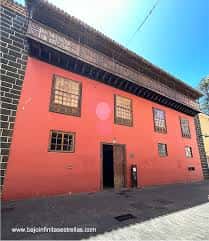 Fachada lateral del edificio en color terracota con ventanas de madera