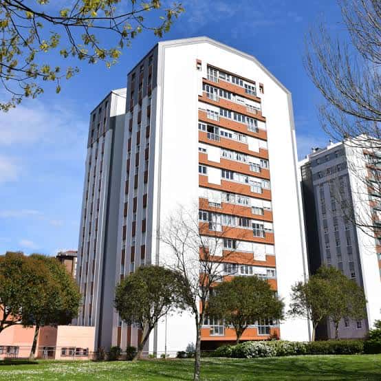 Vista exterior de un edificio residencial moderno en la Calle Puerto del Palo con fachada blanca y detalles en ladrillo