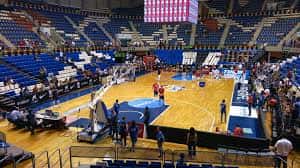 Pabellón interior con cancha de baloncesto y gradas azules