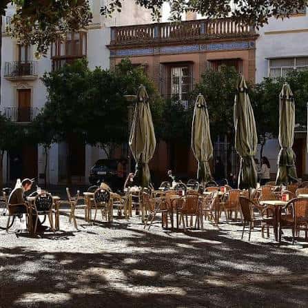 Terraza de cafetería en la Plaza del Banco con sombrillas y mesas al aire libre