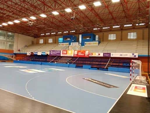 Interior del pabellón mostrando la cancha de balonmano y estructura de techo