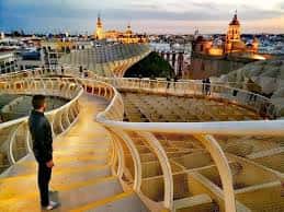 Persona caminando por la pasarela del Metropol Parasol al atardecer con vistas a la Giralda