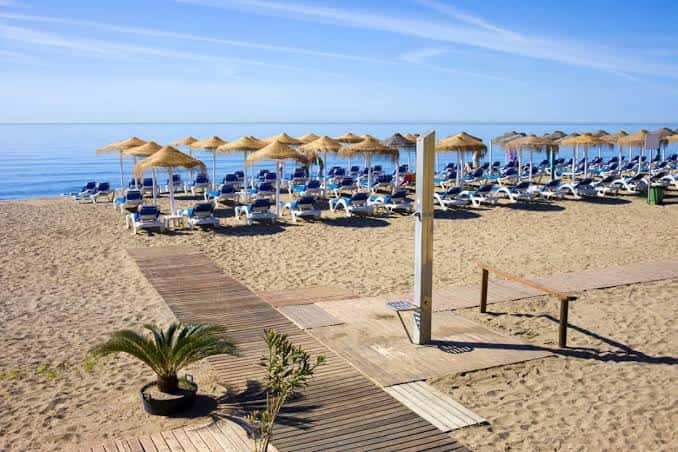 Vista panorámica de la playa con hamacas y sombrillas bajo un cielo despejado