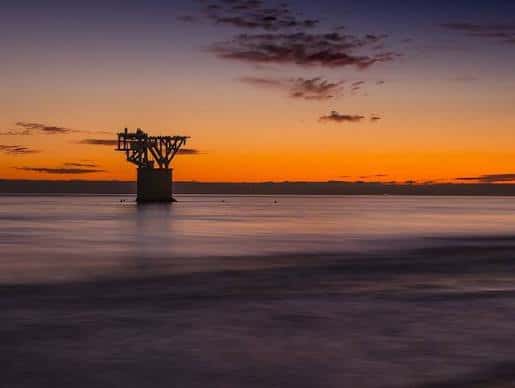 Puesta de sol sobre el mar con la estructura del Cable en el horizonte