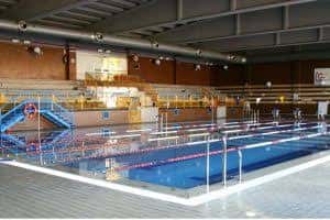Piscina cubierta del polideportivo con gradas y zona de saltos