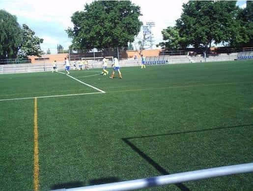 Campo de fútbol con césped sintético y jugadores en actividad