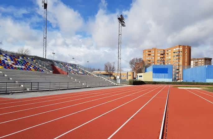 Pista de atletismo con gradas coloridas y torres de iluminación