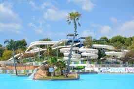 Toboganes blancos y zona de piscina en Aqua Natura Benidorm con palmeras y cielo azul