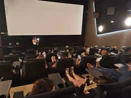 Interior de la sala de cine con butacas modernas y pantalla grande durante una proyección