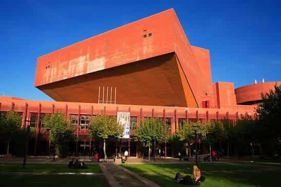 Vista exterior del Auditorio de la Universidad Carlos III de Madrid con su distintiva fachada de hormigón rojizo bajo un cielo azul